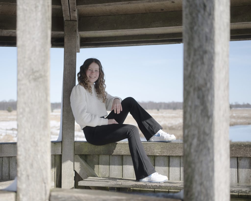 *meisje zittend op een houten relling