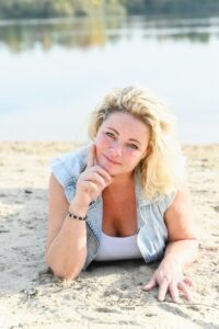 blonde dame liggend in het zand