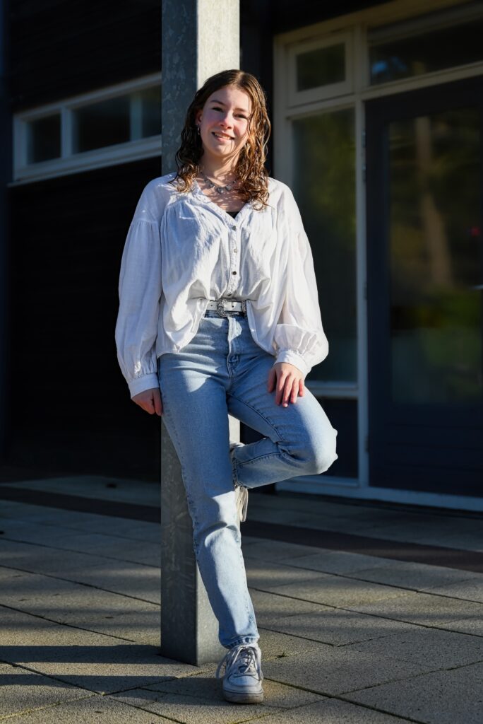 *jonge dame leunend tegen metalen paal